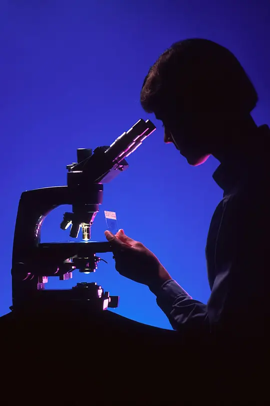 Silhouette of a researcher looking through a microscope