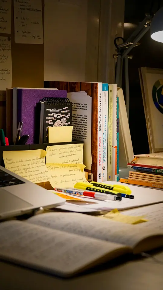 A study desk with textbooks, sticky notes, highlighters and a laptop